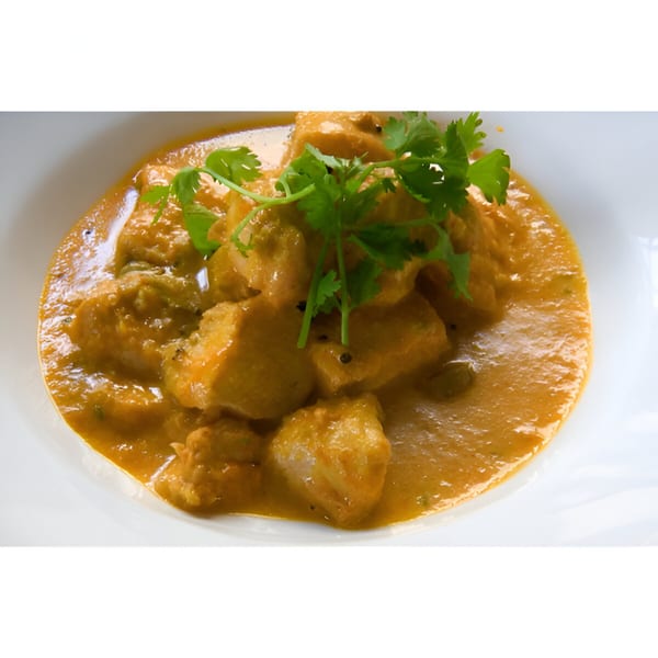 Indian chicken curry with a rich orange sauce, garnished with fresh green cilantro in a white bowl.