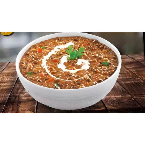 A white bowl of Great Indian Kitchen's creamy Dal Makhani, garnished with fresh cilantro and cream swirls.