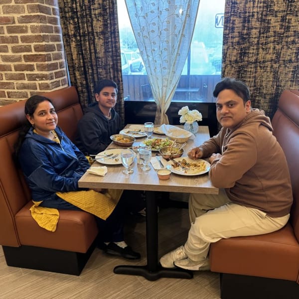 A family of three enjoying Indian food at Great Indian Kitchen, seated at a table with dishes.