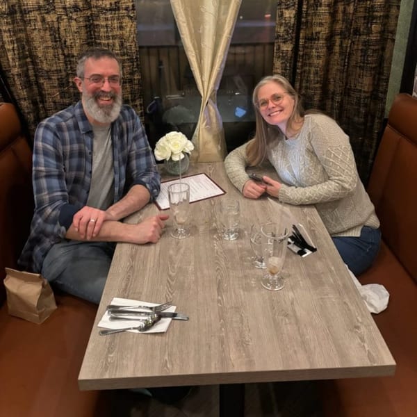 A smiling couple sits at a table in Great Indian Kitchen, ready for their meal.