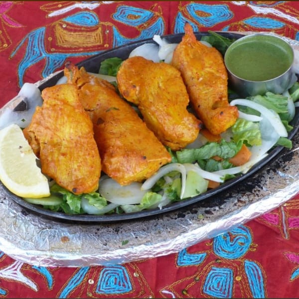 Great Indian Kitchen's chicken tikka, served with lemon, onions, lettuce, and green chutney.