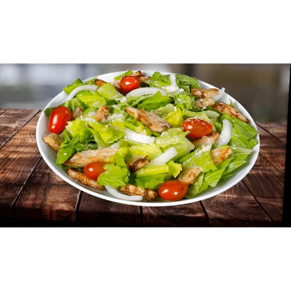 A fresh salad with lettuce, cherry tomatoes, onions, grilled chicken, and grated cheese in a white bowl.